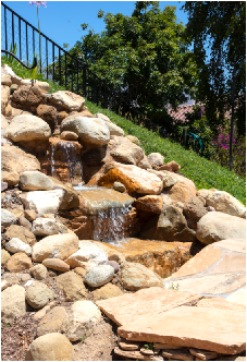 Real Estate Photography of backyard water fountain with rocks and green grass (ChrisRyanPIX)